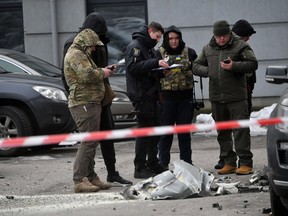 Police experts examine remains of a downed missile which fell on a vehicle parked at a residential building in Kyiv on December 29, 2022, following a Russian missile strike on Ukraine.