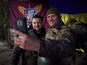 This handout picture taken and released by the Ukrainian Presidential press service on December 6, 2022, shows Ukrainian President Volodymyr Zelensky posing for a selfie with a Ukrainian soldier as he visits the Donetsk region.