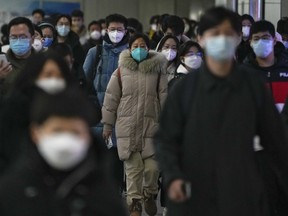 FILE - Masked commuters walk through a walkway in between two subway stations as they head to work during the morning rush hour in Beijing, Tuesday, Dec. 20, 2022. China continues to adapt to an easing of strict virus containment regulations. About three years ago, the original version of the coronavirus spread from China to the rest of the world and was eventually replaced by the delta variant, then omicron and its descendants, which continue plaguing the world today.