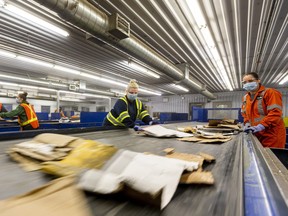 Workers at Miller Waste sort cardboard from paper and plastics on a fast moving conveyor belt as the final step in recycling cardboard at the Material Recovery Facility in London, Ont, on March 23, 2021.