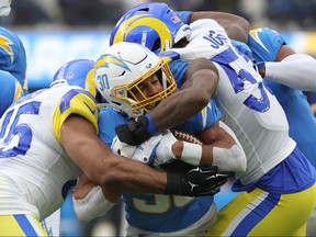 Ernest Jones of the Los Angeles Rams tackles Austin Ekeler of the Los Angeles Chargers during the second quarter at SoFi Stadium on January 01, 2023 in Inglewood, California.