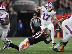Josh Allen of the Buffalo Bills scrambles as Mike Hilton of the Cincinnati Bengals attempts a tackle during the first quarter at Paycor Stadium on January 02, 2023 in Cincinnati, Ohio.