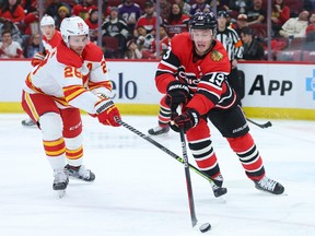 Michael Stone of the Calgary Flames and Jonathan Toews of the Chicago Blackhawks battle for control of the puck during the second period at United Center on January 08, 2023 in Chicago, Illinois.