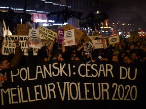 Feminist activists hold a banner reading "Polanski: Best rapist 2020 award" during a demonstration outside the Salle Pleyel in Paris as guests arrive for the 45th edition of the Cesar Film Awards ceremony on February 28, 2020.