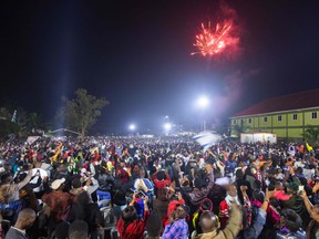 Fireworks light up the sky as people react while they celebrate after counting down to the new year at Miracle Center Cathedral in Kampala, Uganda, on January 1, 2023.