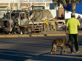 A man passes by a burnt truck on a street