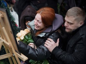 Relatives grieve as they look at the photo of Mykhaylo Korenovsky, a Ukrainian boxing coach, who died following a missile strike last week on a residential building, during his funeral in Dnipro, eastern Ukraine on January 17, 2023.