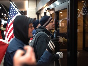 Protesters yell at the door of a hotel where Prime Minister Justin Trudeau is staying during the Liberal Cabinet retreat in downtown Hamilton on Tuesday, January 24, 2023.