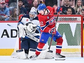Cole Caufield of the Montreal Canadiens screens goaltender Connor Hellebuyck of the Winnipeg Jets as he makes a save at Centre Bell on January 17, 2023 in Montreal.
