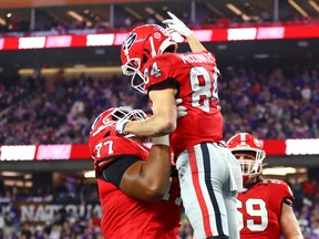 Georgia Bulldogs offensive lineman Devin Willock (77) lifts up wide receiver Ladd McConkey (84) during the CFP national championship game at SoFi Stadium.