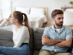 Man and woman sit separately on couch after fight