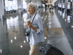 Senior lady walking with camera at airport