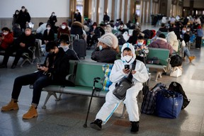 A person wearing a protective suit sits in Beijing Railway Station as passengers wait to board a train to travel for Spring Festival ahead of Chinese Lunar New Year festivities after China lifted its COVID-19 restrictions in Beijing, Jan. 20, 2023.