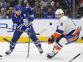 Nov 21, 2022; Toronto, Ontario, CAN; New York Islanders defenseman Ryan Pulock (6) and Toronto Maple Leafs forward Mitchell Marner (16) play for the puck during the first period at Scotiabank Arena.