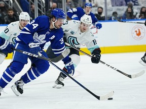 Toronto Maple Leafs forward Auston Matthews carries the puck past Seattle Kraken forward Jared McCann during the second period at Scotiabank Arena.