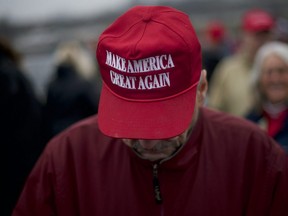 A Trump supporter wears a "MAKE AMERICA GREAT AGAIN" hat while waiting in the rain before then-U.S. President Donald J. Trump holds a campaign rally in Hershey, Pa., Dec. 10, 2019.