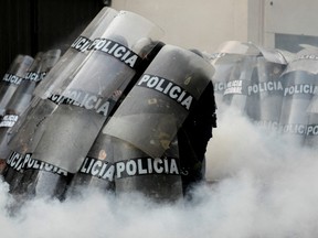 Riot police officers take cover as they clash with demonstrators during the "Take over Lima" march to demonstrate against Peru's President Dina Boluarte, following the ousting and arrest of former President Pedro Castillo, in Lima, Peru Jan. 19, 2023.