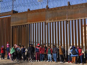 Migrants from Nicaragua, Ecuador and other nationalities are pictured at a door on the border wall waiting to be picked up by the U.S. Border Patrol in El Paso, Texas, Wednesday, Jan. 4, 2023.