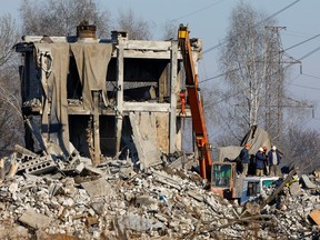 Workers remove debris of a destroyed building purported to be a vocational college used as temporary accommodation for Russian soldiers, 63 of whom were killed in a Ukrainian missile strike, January 3, 2023.