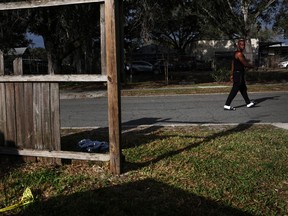 A man walks by police tape near a crime scene, where according to local media there are reports of at least 10 people wounded in a drive-by shooting Monday afternoon, in a residential area of Lakeland, Fla., Jan. 31, 2023.