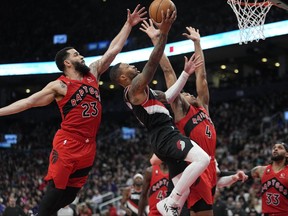 Portland Trail Blazers guard Gary Payton II (0) goes to the basket as Toronto Raptors guard Fred VanVleet (23) and forward Scottie Barnes (4) defend during the second half at Scotiabank Arena.