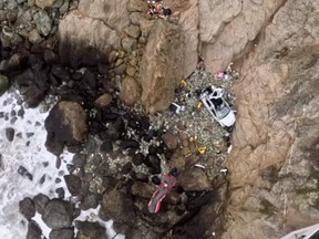 A crash victim is lifted to a helicopter during a rescue operation after a vehicle carrying two adults and two children went over a cliff in Devil's Slide, San Mateo county, Calif., Monday, Jan. 2, 2023, in this still image obtained from social media video.