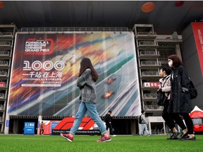 Formula One F1 - Chinese Grand Prix - Shanghai International Circuit, Shanghai, China - April 11, 2019     People walk past a poster for the Chinese Grand Prix, Formula One's 1,000th world championship race.