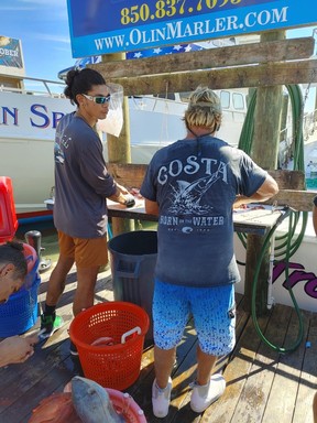 Crew of a Destin fishing charter boat clean their catch at the harbour.