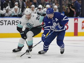 Toronto Maple Leafs forward Mitchell Marner and Seattle Kracken defenseman Jamie Oleksiak battle for the puck during the first period at Scotiabank Arena.