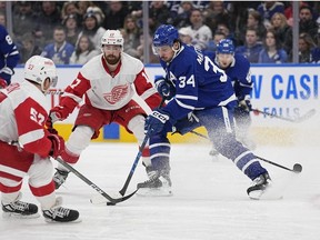 Toronto Maple Leafs forward Auston Matthews tries to carry the puck past Detroit Red Wings forward David Perron and defenseman Filip Hronek during the third period at Scotiabank Arena.