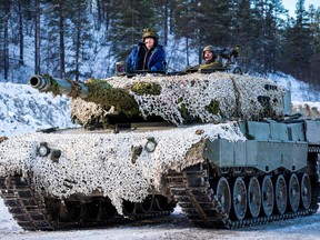 Norway's Prime Minister Erna Solberg, left, looks out of a Leopard 2 battle tank in the Roros area, central Norway, during NATO exercise Trident Juncture, on Oct. 27, 2018.