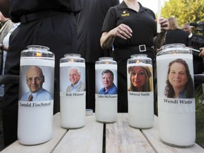 Photos of five employees of the Capital Gazette newspaper adorn candles during a vigil, June 29, 2018, across the street from where they were slain in the newsroom in Annapolis, Md.