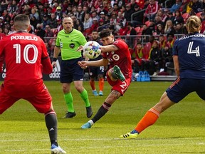 Toronto FC midfielder Jonathan Osorio kicks the ball between midfielder Alejandro Pozuelo and FC Cincinnati defender Nick Hagglund during the first half at BMO Field.