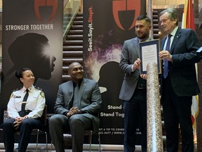 Toronto Mayor John Tory (far right) gives January Crime Stoppers Month proclamation to Toronto Crime Stoppers Chair Sean Sportun while Toronto Crime Stoppers Coordinator, Det. Marc Madramootoo, and Toronto Police Service Deputy Chief Lauren Pogue (far left) look on.