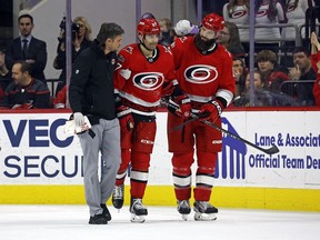 Carolina Hurricanes head athletic trainer Doug Bennett, left, and Brent Burns, right, assist Max Pacioretty off the ice following an injury during the third period of the team's NHL hockey game against the Minnesota Wild in Raleigh, N.C., Thursday, Jan. 19, 2023.