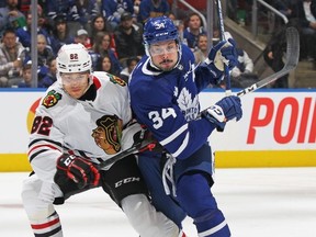 Caleb Jones of the Chicago Blackhawks battles against Auston Matthews of the Toronto Maple Leafs at Scotiabank Arena on February 15, 2023 in Toronto, Ontario, Canada.