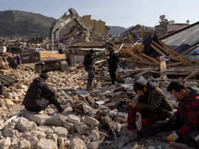 Relatives watch and wait as rescuers search for their missing family members amid the rubble following the deadly earthquake in Hatay province, Turkey, February 14, 2023.