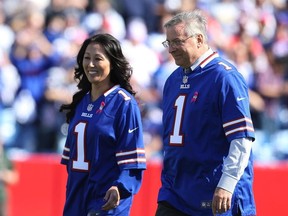 Terry Pegula (R), the new owner of the Buffalo Bills, and his wife Kim Pegula, take the field before the first half against the New England Patriots at Ralph Wilson Stadium on October 12, 2014 in Orchard Park, New York.