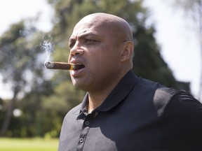 NBA Hall of Famer Charles Barkley looks on while smoking a cigar at a golf tournament.