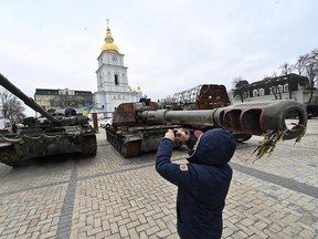 A man takes pictures of destroyed Russian military vehicles shown in an open air exhibition in the centre of Kyiv on Feb. 24, 2023 on the first anniversary of the Russian invasion of Ukraine.