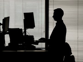 A man works at a computer on a standing desk in an office in the financial district of Canary Wharf in London, Feb. 8, 2023.