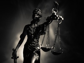 The Statue of Justice - lady justice or Iustitia / Justitia the Roman goddess of Justice on a dark fire background. Getty Images/iStockphoto
