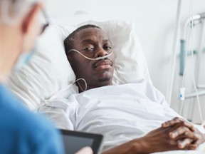 An African-American man lying down on a hospital bed.