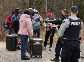 Asylum seekers talk to a police officer as they cross into Canada from the U.S. border near a checkpoint on Roxham Road near Hemmingford, Quebec, April 24, 2022. REUTERS/Christinne Muschi