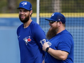 Toronto Blue Jays designated hitter and first baseman Brandon Belt, left, smiles as he talks with a member of the Blue Jays training staff during baseball spring training in Dunedin, Fla., on Tuesday, February 21, 2023.