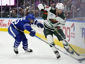 Minnesota Wild's Jordan Greenway protects the puck from Maple Leafs' Mark Giordano during first-period NHL  action in Toronto on Friday, February 24, 2023.