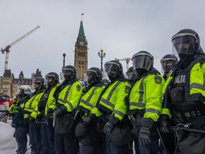 Police face off with demonstrators participating in a protest organized by truck drivers opposing vaccine mandates on Wellington St. on February 19, 2022 in Ottawa, Ontario. The drivers have used vehicles to form a blockade that has blocked several streets near Parliament Hill.  Prime Minister Justin Trudeau has invoked the Emergencies Act in an attempt to try to put an end to the demonstration that has nearly paralyzed a portion of downtown Ottawa for three weeks.  (Photo by Alex Kent/Getty Images)