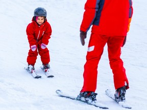Professional ski instructor teaching a child to ski on a sunny day