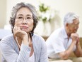 Senior asian couple sitting on couch at home, angry at each other