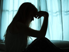 Silhouette of a woman sitting in bed by a window.